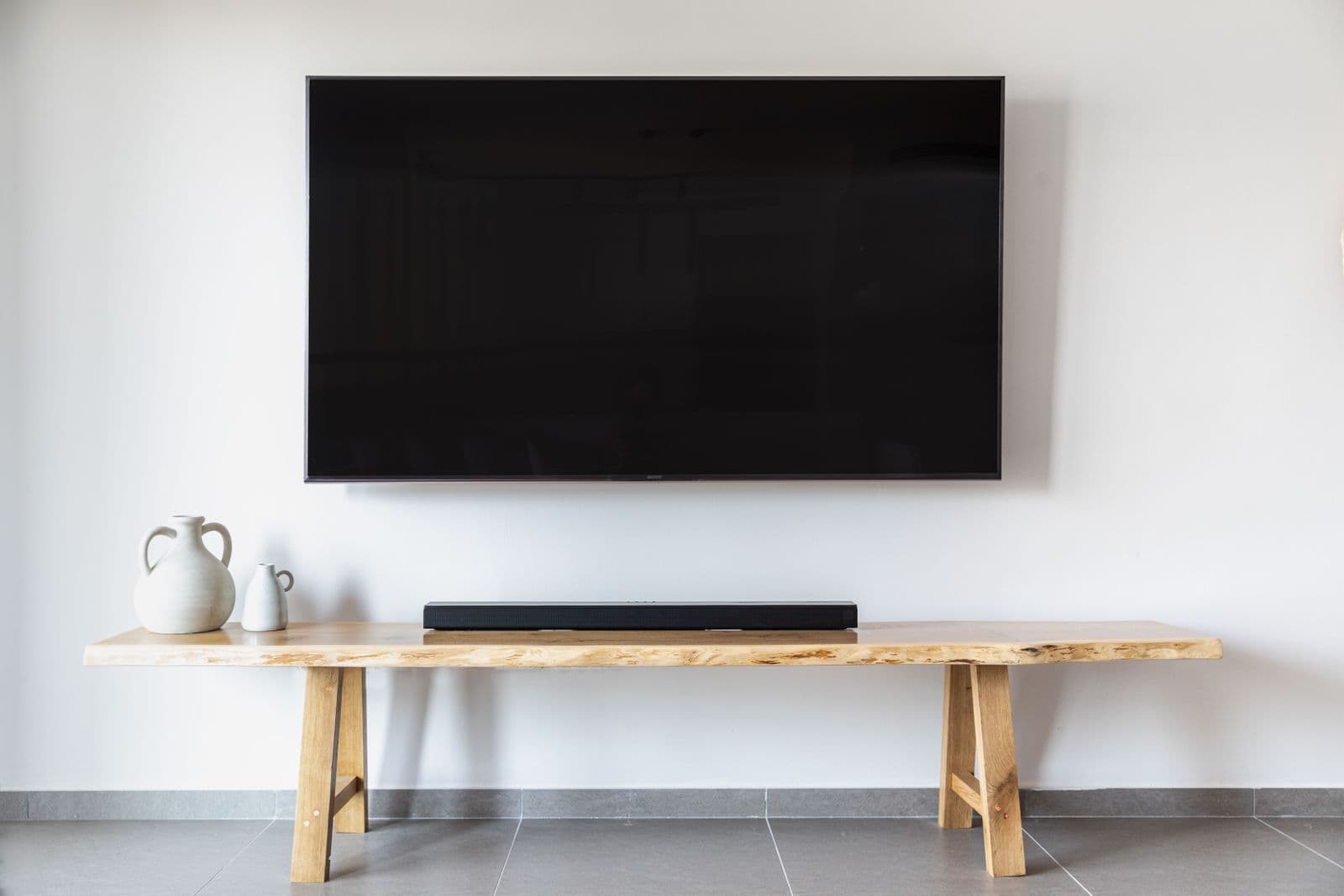 Large flat-screen TV neatly wall-mounted above a wooden bench with a soundbar