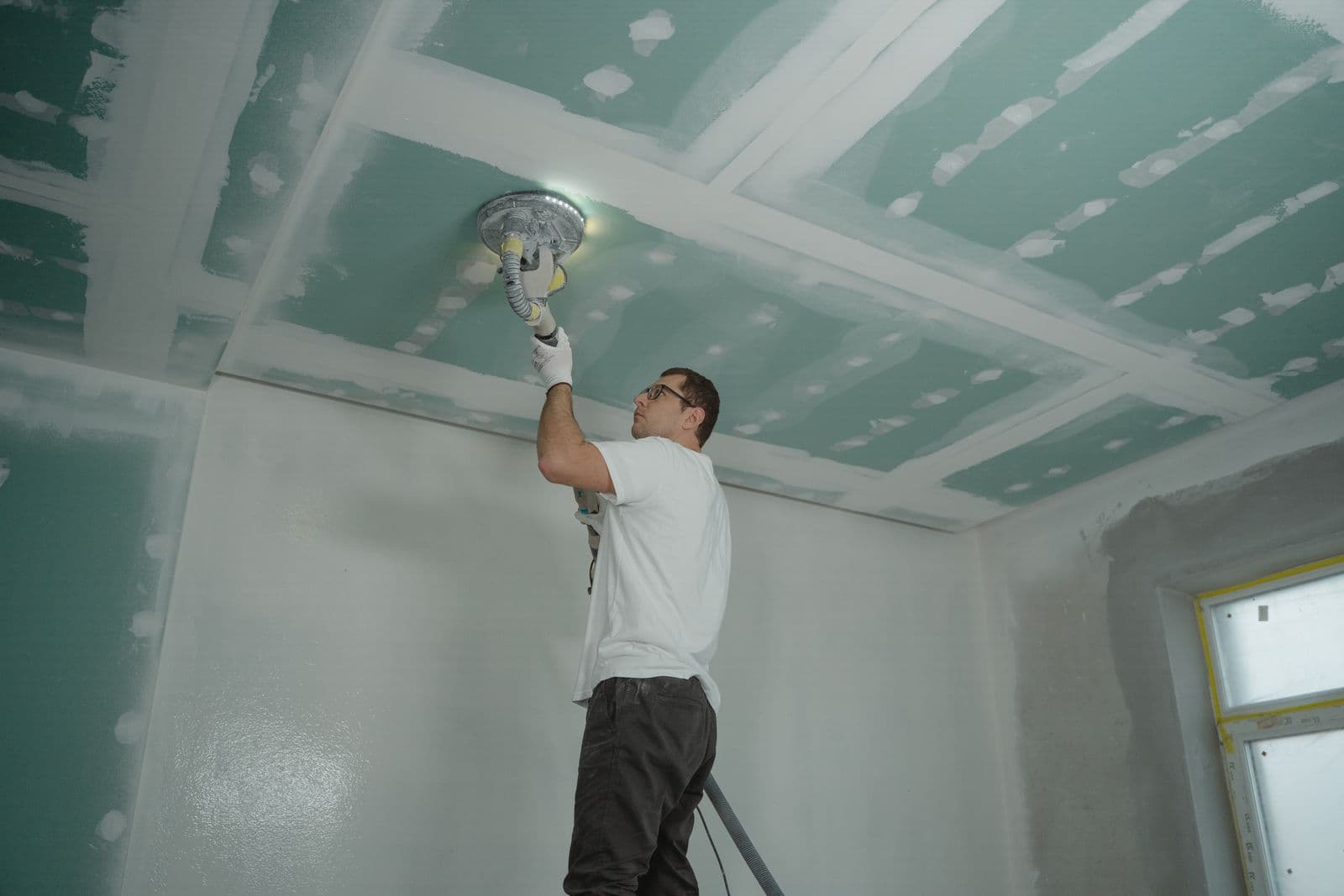 Pro smoothing a freshly repaired ceiling before painting