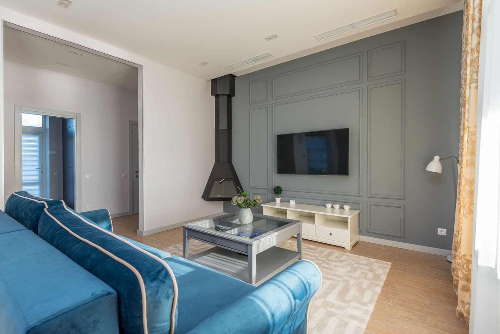 Living room with a wall-mounted TV and a blue couch